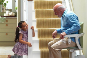 a small girl holding stair railing while an elderly man utilizes one of many Used Stair Lifts in South Jersey, Philadelphia, Wilmington, Ardmore, Moorestown, King of Prussia